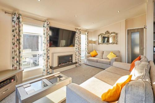 a living room with a couch and a fireplace at Penny Lodge with Hot Tub in Malton