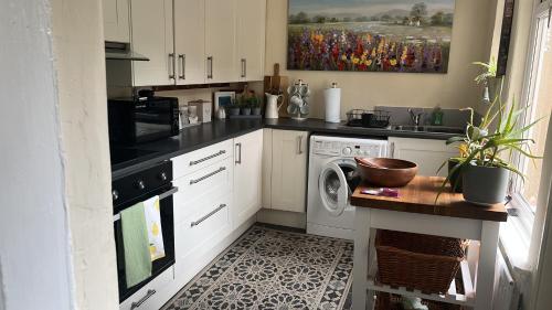 a kitchen with white cabinets and a washer and dryer at stone cottage in Fir Tree