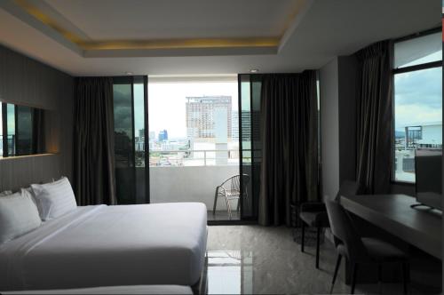 a hotel room with a bed and a desk and windows at Hermann Hotel Pattaya in Pattaya