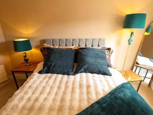 a bedroom with a bed with blue pillows and two lamps at 35 Wrawby Street in Brigg
