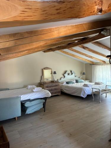 two beds in a room with wooden ceilings at El gallinero de Valoria in Valoria la Buena