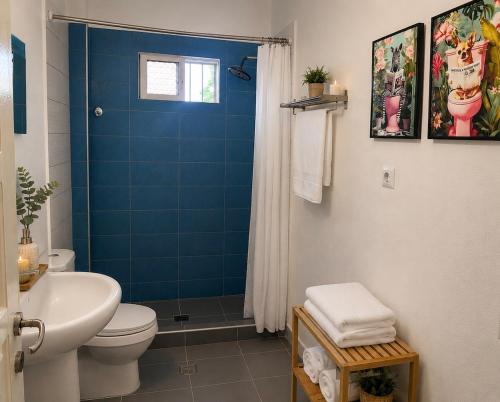 a blue tiled bathroom with a toilet and a shower at Stavros Green & Sea Holiday Home in Stavros