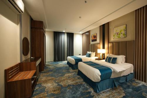 a hotel room with two beds and a television at جولدن بوجاري الضيافه in Khamis Mushayt