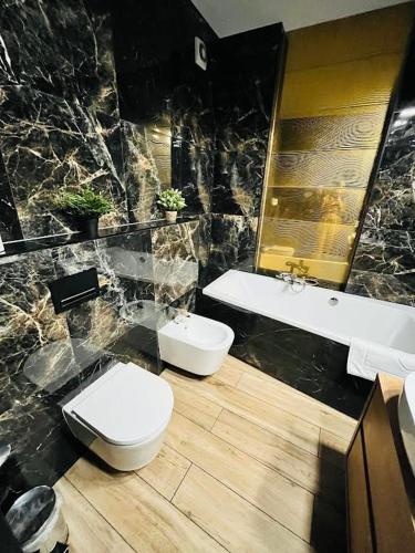 a bathroom with two toilets and a sink and a tub at Tesao Room by Dworek Marino in Grzybowo