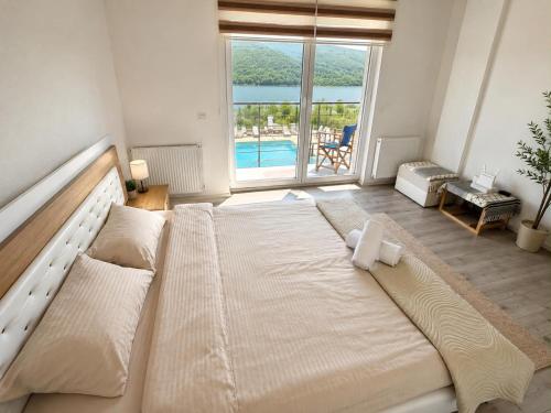 a large bed in a room with a large window at LUX Villa Mavrovo in Mavrovo