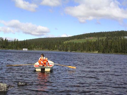 a man and a child in a boat on a lake at Løstegård hytter at the top of Golsfjellet in Gol