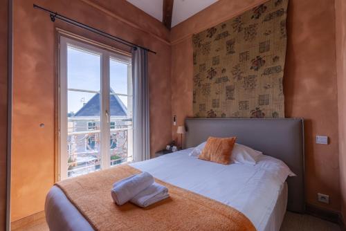 a bedroom with a bed and a large window at Logis hotels Les Glycines in Melle