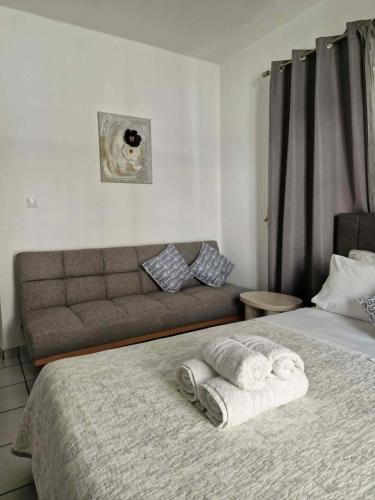 a bed with towels and a couch in a bedroom at Olimpus Sunset Studio in Paralia Katerinis