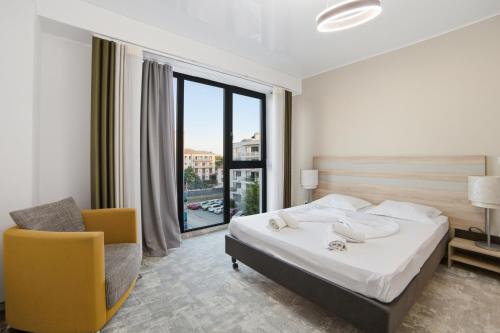 a bedroom with a bed and a chair and a window at Apartaments PopDan Residence by the Sea in Eforie Nord
