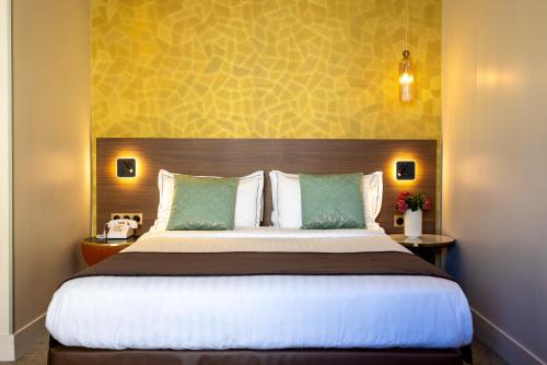 a bedroom with a large bed with a large headboard at Hotel Parc Eiffel in Paris