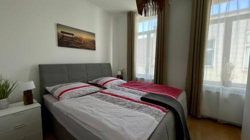 a bed in a bedroom with two windows at MEERzeit-Norderney in Norderney