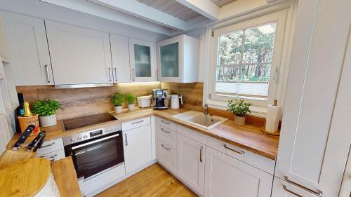 a kitchen with white cabinets and a sink and a window at Strandhaus Rügenperle - Baabe in Baabe