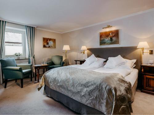 a hotel room with a large bed and two chairs at Fletcher Berghotel Astenkrone-Winterberg in Winterberg