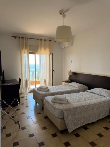 a bedroom with two beds and a piano and a window at Hotel Solemar in SantʼAlessio Siculo
