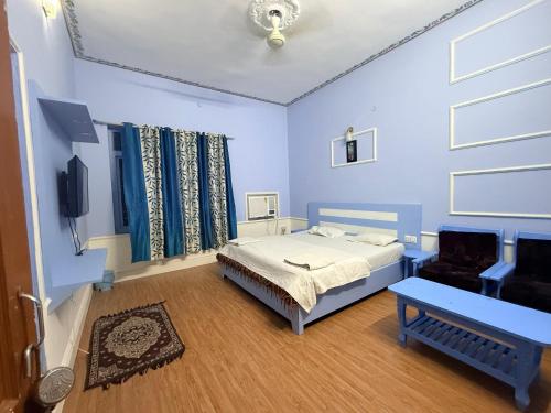 a blue bedroom with a bed and a chair at Hotel Prem Villas Pushkar in Pushkar