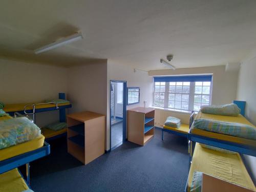 a room with three beds and a desk and a mirror at Adventure Bude in Bude