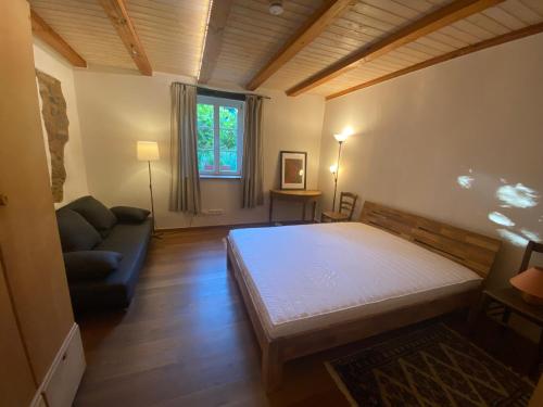 a bedroom with a bed and a couch and a window at Auf der Saarinsel in Kanzem