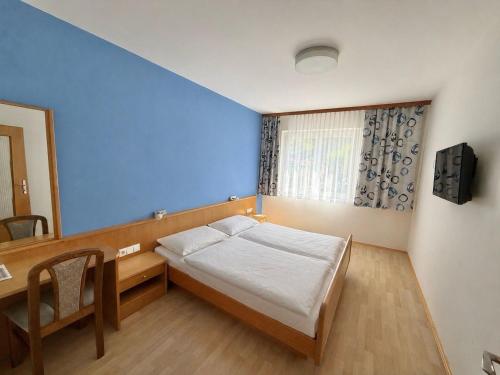 a bedroom with a bed and a desk and a window at Gästehaus Kremser in Weiten