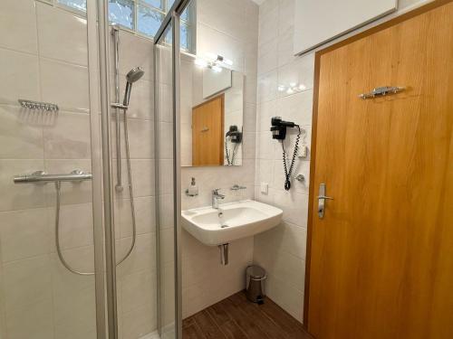 a bathroom with a sink and a shower with a glass door at Gästehaus Kremser in Weiten