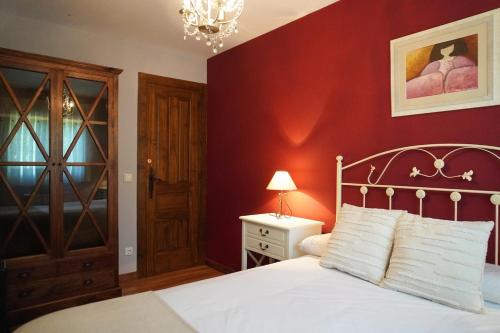 a bedroom with a white bed and a red wall at Villa Pereza in Socueva