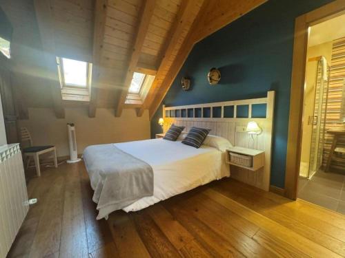 a bedroom with a large white bed with blue walls at Hostal Casa Otsoa in Ezcároz
