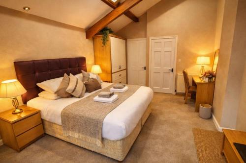 a bedroom with a large bed and a desk at Dolgun Uchaf Historic B&B and Cottages with Boutique Bedrooms In The Heart of Snowdonia in Dolgellau
