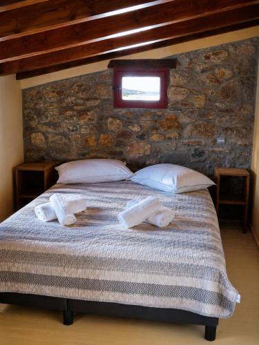 a bedroom with a bed with pillows and a window at Thetis Stone Residence in Volissos