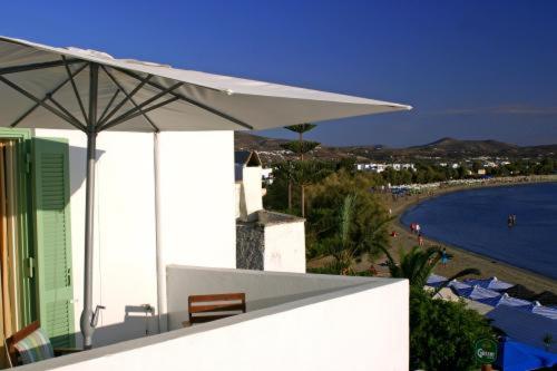 un edificio bianco con ombrellone e spiaggia di Sigma Studios on The Beach a Naxos Chora
