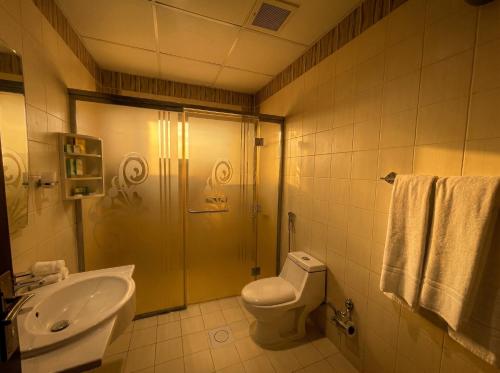 a bathroom with a shower and a toilet and a sink at Tulip Al Rawda Serviced Apartments in Riyadh
