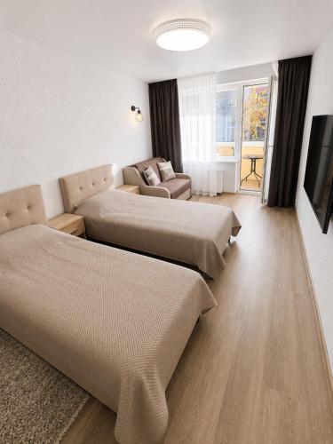 a living room with two beds and a couch at Taikos apartamentas in Mažeikiai