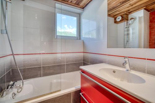 a bathroom with a sink and a tub and a mirror at Appartement Tommeuse 93 in Tignes
