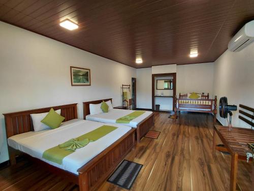 two beds in a room with wooden floors at Kandy Riverside Villa in Kandy