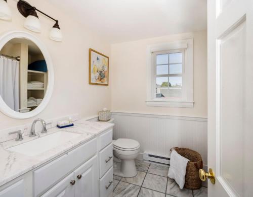 a white bathroom with a toilet and a mirror at The Boathouse in Kennebunkport