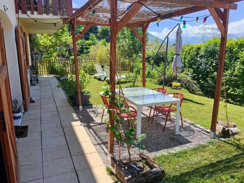 a patio with a table and chairs under a pergola at L'Aparté Nature, entre campagne et montagne in Jarrie