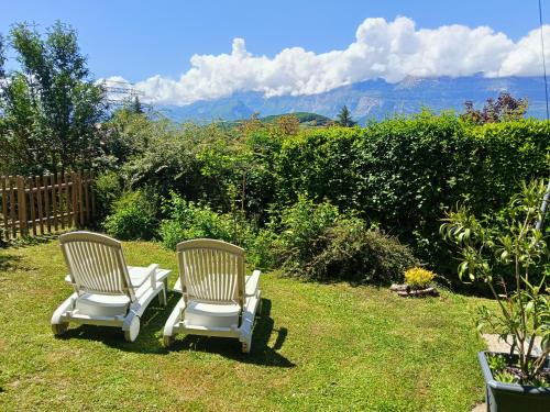 two chairs sitting in the grass with mountains in the background at L'Aparté Nature, entre campagne et montagne in Jarrie