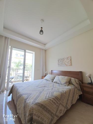 a bedroom with a large bed and a large window at Chaleureux appartement in Bouznika