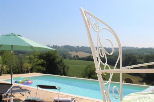 a swimming pool with two chairs and an umbrella at Lôu cayrou in Beaumarches