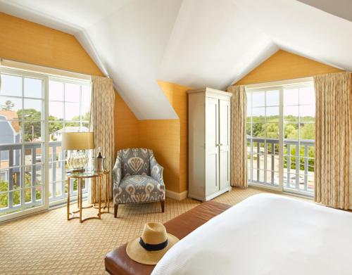 a bedroom with a bed and a chair and windows at The Grand Hotel in Kennebunk