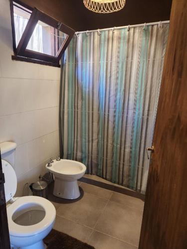 a bathroom with a toilet and a shower curtain at La Gauda in Huacalera