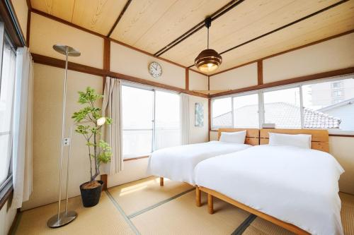 two beds in a room with windows at Kokonimo Kawagoesenba in Kawagoe