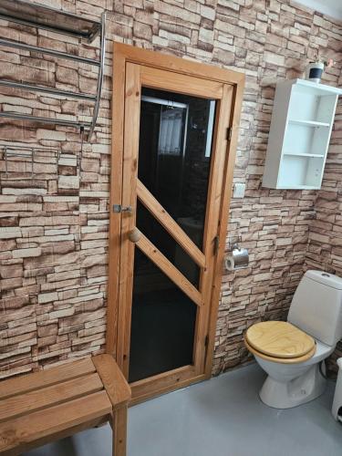 a bathroom with a wooden door and a toilet at Milas House two apartments in Fredvang