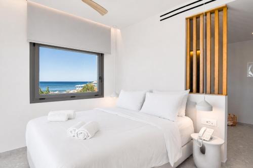 a white bedroom with a large white bed and a window at enplomare in Plomari
