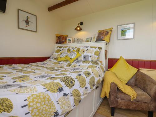 a bedroom with a bed and a chair at The Herdsman Luxury Shepherds Hut in Barnoldswick