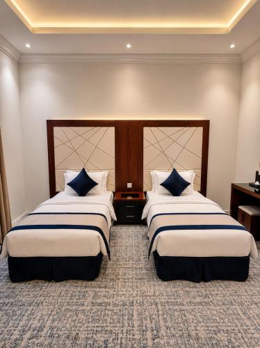 a hotel room with two beds with blue and white pillows at Al Quba Palace Serviced Apartments in Riyadh