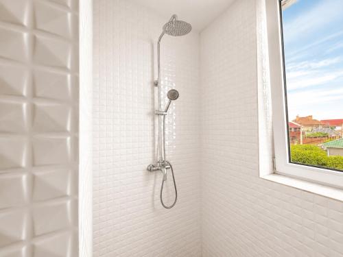 a shower in a white tiled bathroom with a window at Qzone 2 in Chornomorsk