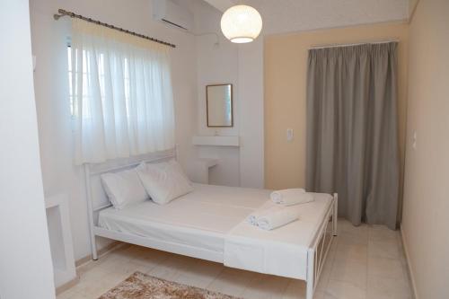 a white bedroom with a bed and a window at Linovrochi holiday house with private pool in Lefkandi Chalkidas
