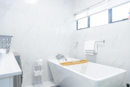 a white bathroom with a tub and a sink at Millenium Heights Borrowdale in Harare