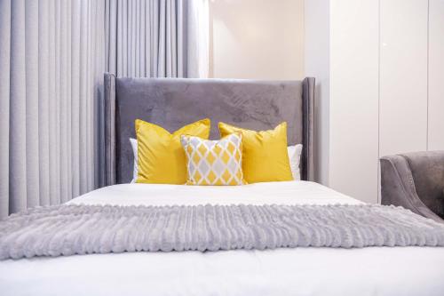 a bedroom with a bed with yellow pillows at Millenium Heights Borrowdale in Harare