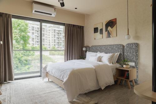 a bedroom with a large bed and a large window at Abhibha Suites Waterfront in Pune