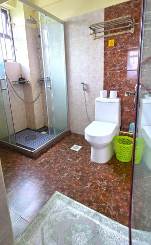 a bathroom with a toilet and a glass shower at The African Artisan 3BR Apartment in Nairobi